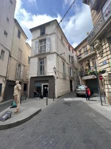 Un uomo in piedi su una strada di fronte a un edificio di Confort Appart a Béziers