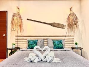 Due cigni bianchi seduti su un letto con una mazza da baseball di Sea Dreamer Beachfront Apartments a Phuket