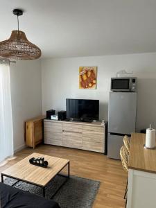 ein Wohnzimmer mit einem Kühlschrank und einem Tisch in der Unterkunft L’appartement du bonheur in Colombes