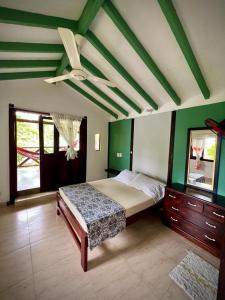 a bedroom with a bed and a ceiling with green walls at Hostal Portal Del Sol in Capurganá