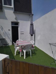 a patio with a table and chairs and an umbrella at Les Hirondelles in Berck-sur-Mer
