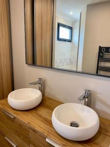 a bathroom with two sinks on a wooden counter with a mirror at T3 - Centre - 75m2 - 2 SDB - Parking - Calme in Anglet +10 photos