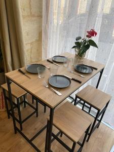 uma mesa de madeira com cadeiras e pratos e um vaso com uma rosa vermelha em Appartement cozy à 100m de la gare Saint Jean em Bordeaux