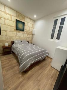 um quarto com uma cama grande e uma parede de pedra em Appartement cozy à 100m de la gare Saint Jean em Bordeaux