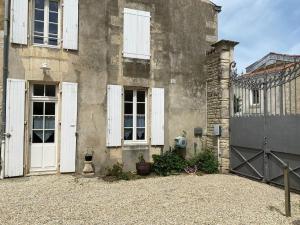 ein altes Haus mit weißen Türen und einem Zaun in der Unterkunft Studio du Puits sainte Claire in Courçon