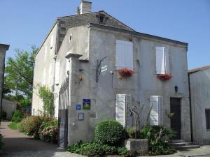 ein altes graues Gebäude mit Blumen an den Fenstern in der Unterkunft Studio du Puits sainte Claire in Courçon