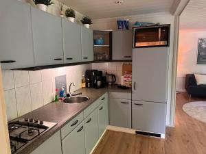 een keuken met witte kasten en een koelkast bij BEEKBERGEN staying in the WOODS freestanding chalet WASMACHINE ALL COUNTRY TV CHANNELS EXPATS WELCOME in Beekbergen