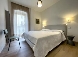 a bedroom with a bed and a chair and a window at Ancora Suites in Bardolino