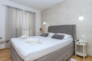 een slaapkamer met een groot wit bed met een grijs hoofdeinde bij Apartment Mirjana in Makarska