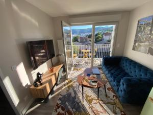 a living room with a blue couch and a large window at Appart T2 avec parking, loggia, vue Puy de Dôme in Clermont-Ferrand