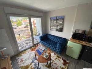 a living room with a blue couch and a large window at Appart T2 avec parking, loggia, vue Puy de Dôme in Clermont-Ferrand