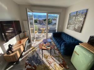 克莱蒙费朗Appart T2 avec parking, loggia, vue Puy de Dôme的客厅设有蓝色的沙发和大窗户