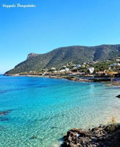 a beach with blue water and a mountain in the background at Pool apartment 5 minutes walk from beach in Porto Rafti