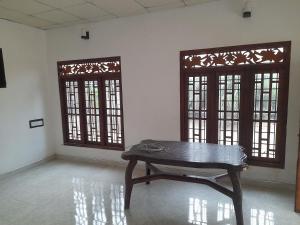 a room with a wooden table and two windows at Rosa Kusum Vacation Home Near Kudawa Beach In Kalpitiya in Kalpitiya