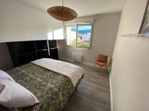 克莱蒙费朗Appart T2 avec parking, loggia, vue Puy de Dôme的一间带床、窗户和椅子的卧室