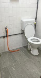 a bathroom with a toilet with an orange hose at CikSiti homestay02 in Kajang