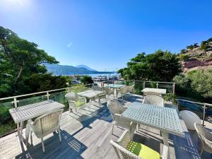 een terras met tafels en stoelen en uitzicht op het water bij Hotel Porto Sole in Sutomore