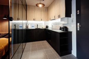 a kitchen with wooden cabinets and a black counter top at Apartament Incognito Rynek in Tarnobrzeg
