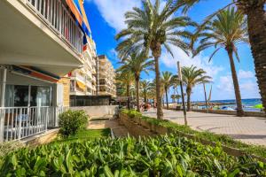 a building on the beach with palm trees and a sidewalk at Bello Horizonte ONLY FAMILIES in Salou