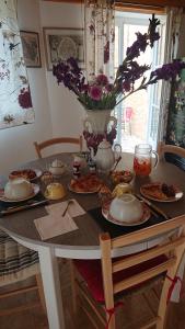 una mesa con platos de comida y un jarrón de flores en Les Mésanges 