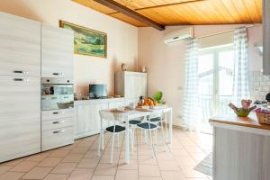 a kitchen with white cabinets and a table with chairs at Un passo dal MARE Due dall'ETNA in Giardini Naxos