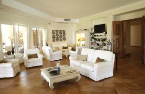 un soggiorno con sedie bianche e tavolino da caffè di Hotel Cala Caterina a Villasimius