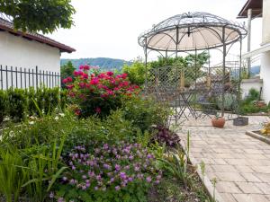 - un jardin avec des fleurs roses et un parasol dans l'établissement Hiša Magnolija, à Tolmin