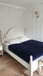 1 dormitorio con cama blanca y manta azul en Stylowy apartament ARMINA, en Szczytno
