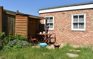 a table in a yard next to a brick building at The Owl Box: self-contained private annex & garden in Horseheath