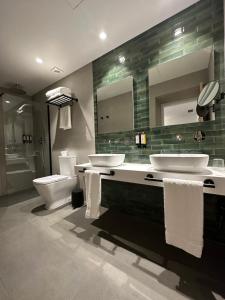 a bathroom with two sinks and a toilet and a mirror at Hotel El Rosal de Cudillero in Cudillero