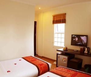 a hotel room with two beds and a television at Rising Dragon Hotel in Hanoi