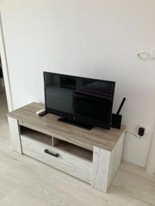 una TV a schermo piatto seduta sopra un centro di intrattenimento in legno di Harmony Relax a Paraćin