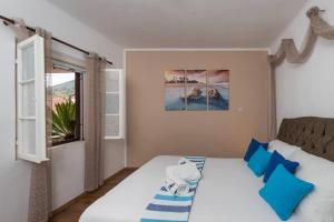 a bedroom with a bed with blue pillows and a window at Bougainvillea in Ston