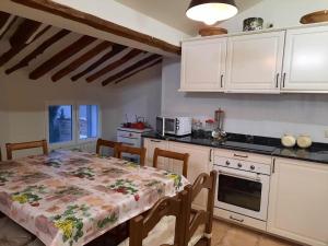 uma cozinha com uma mesa e uma cozinha com armários brancos em Las Casas del Rincón -4 dormitorios em Villahermosa