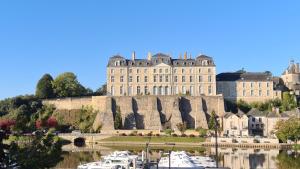 a large castle with boats in the water in front at A appartement Cozy, vue sur le port, gîte, les pieds dans l'eau in Sablé-sur-Sarthe