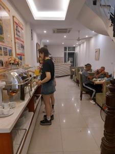 a woman standing behind a counter in a restaurant at Rising Dragon Hotel in Hanoi