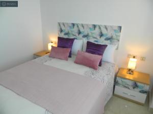 um quarto com uma grande cama branca com almofadas roxas em BLUE 470 em Isla Cristina