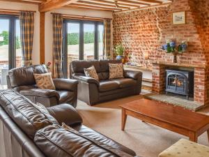 a living room with leather furniture and a fireplace at Oak Barn in Felbrigg