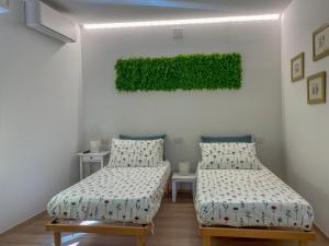 een kamer met 2 bedden en een groen schilderij aan de muur bij Il giardino dei portici in Medicina
