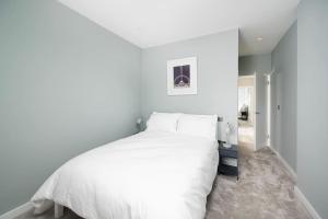 a bedroom with a large white bed and a hallway at Oak Tree Lodge in London