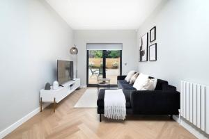 a living room with a black couch and a tv at Oak Tree Lodge in London