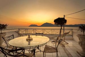 a table and chairs on a balcony with the sunset at Rio Beach Residence in Patra
