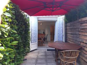 a red umbrella over a table and chairs on a patio at La ferme de Manon in Montferrat