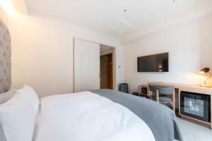 a bedroom with a bed and a desk and a tv at The knot Sapporo - Vacation STAY 96399v in Sapporo