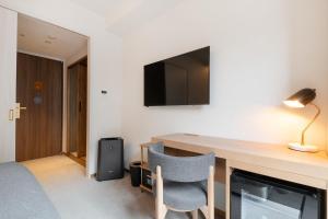 a hotel room with a desk and a tv on the wall at The knot Sapporo - Vacation STAY 96399v in Sapporo