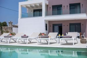 a group of white lounge chairs next to a swimming pool at Villa Aurora in Faliraki