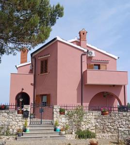 une maison rose avec des escaliers devant elle dans l'établissement Sobe Bukaleta Loznati, à Loznati