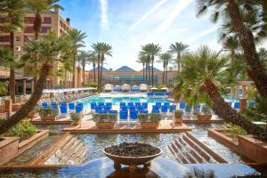 a pool at a resort with palm trees and blue chairs at Renaissance Esmeralda Resort & Spa, Indian Wells in Indian Wells