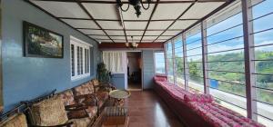 a living room with couches and windows at Heath Cote in Ooty