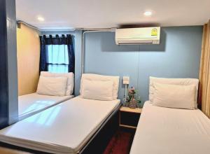 a room with two beds and a air conditioner at Check-in My Hostel in Bangkok
